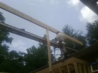 Carpenter setting a ridge beam over a new addition frame — Ice Dam Removal by Roofing Brothers in Terrell