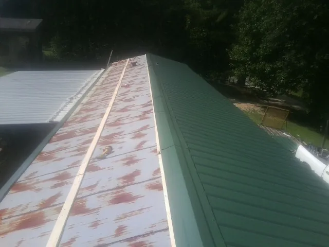 Old rusted panels beside newly installed green metal roofing — Wind Damage Roof Repair by Roofing Brothers in Terrell