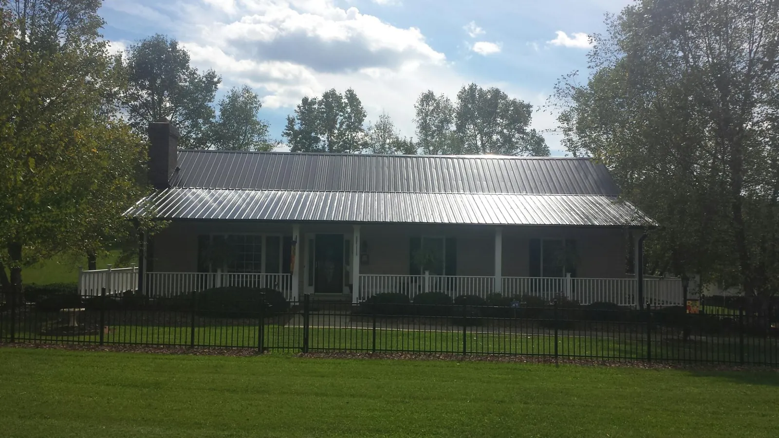 Gray metal roof on a brick ranch with a full width front porch — Gutter Guard Installation work by our crew in Terrell