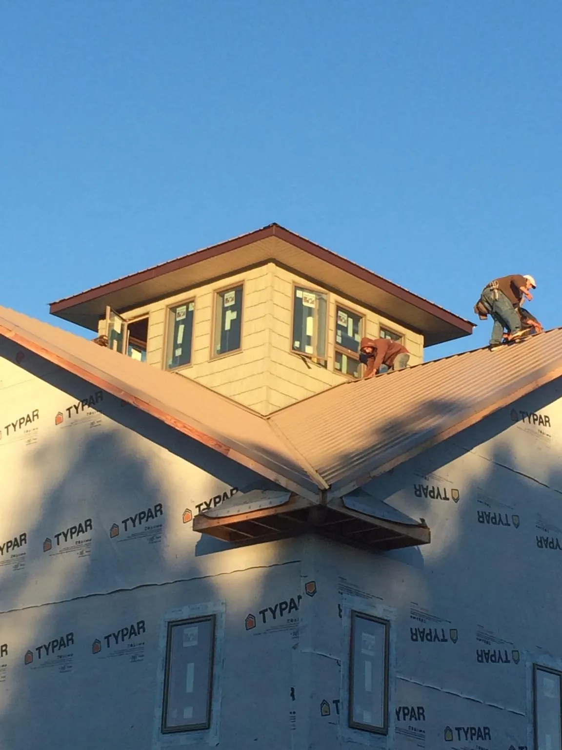 Roofers working around a rooftop cupola on a new metal roof at sunset — Roof Waterproofing in Terrell by Roofing Brothers